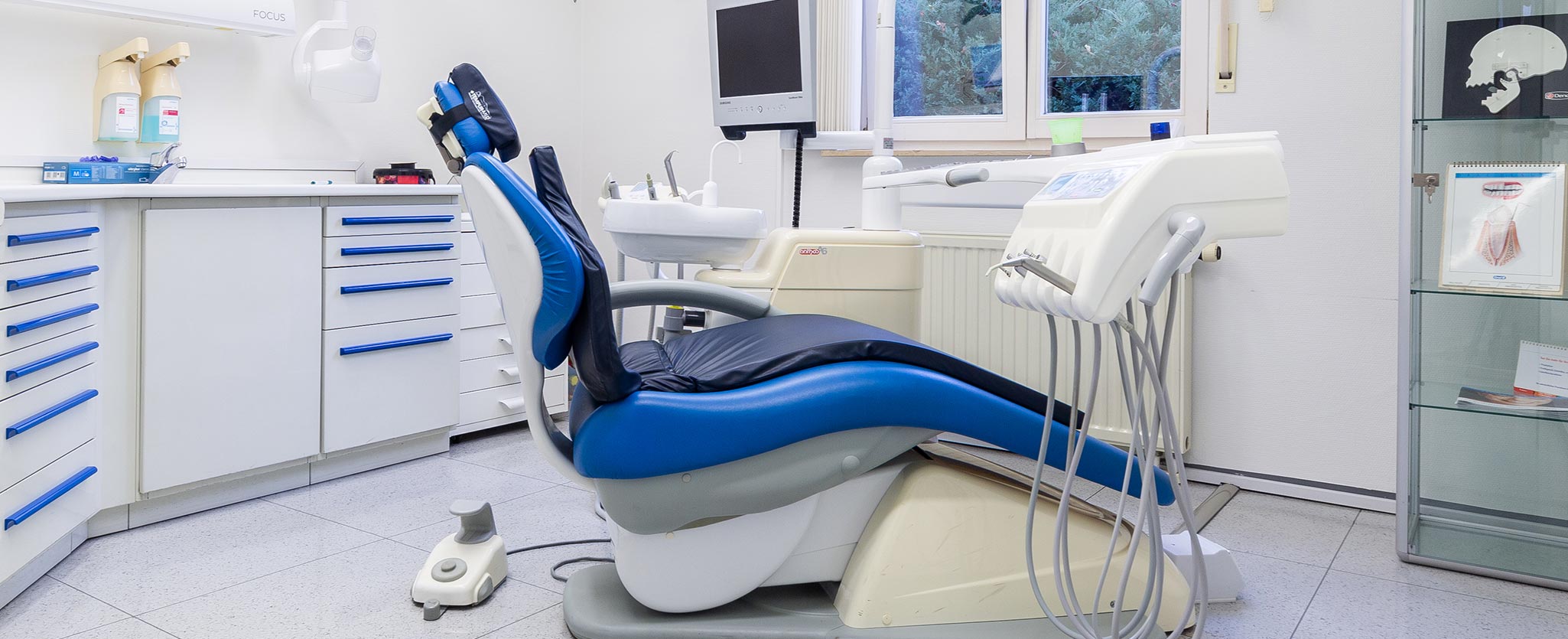 Foto vom Behandlungszimmer der Zahnarztpraxis Totolici in Konstanz mit blau gepolsterten Behandlungsstuhl und diversen Zahnärztlichen Geräten
