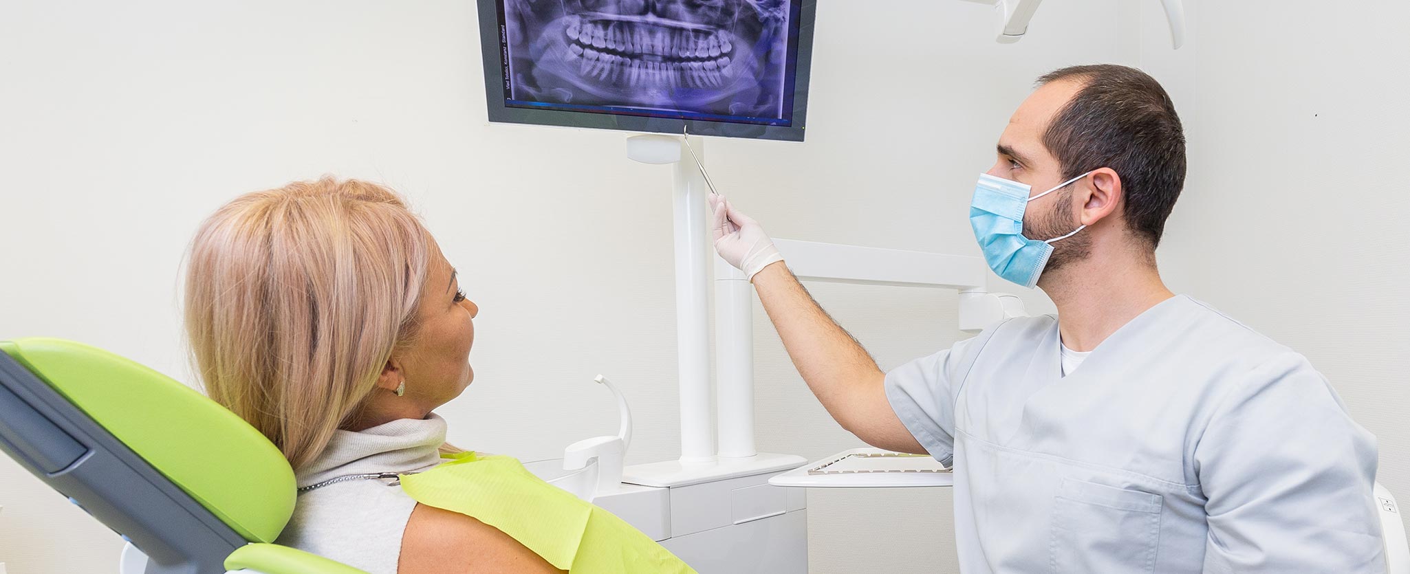 Foto von Zahnarzt Totolici, der einer Patientin ein Röntgenbild erklärt im Behandlungszimmer
