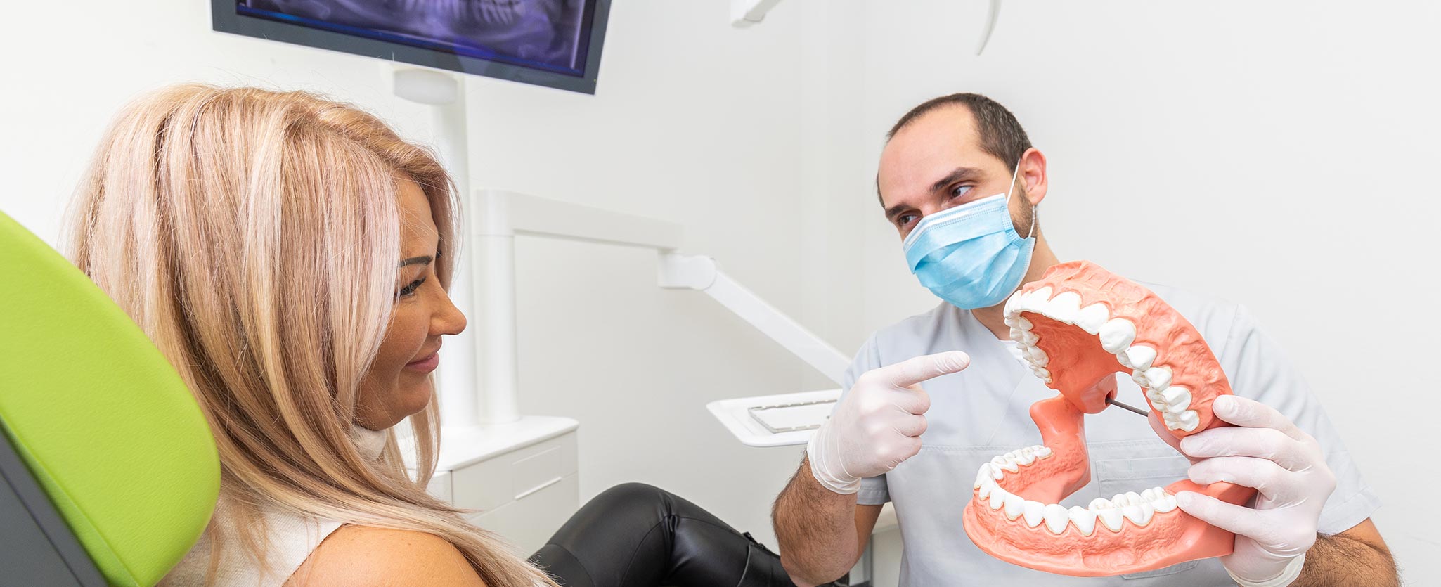 Foto von Zahnarzt Totolici, der einer Patientin an einem Gebiss-Modell etwas erklärt