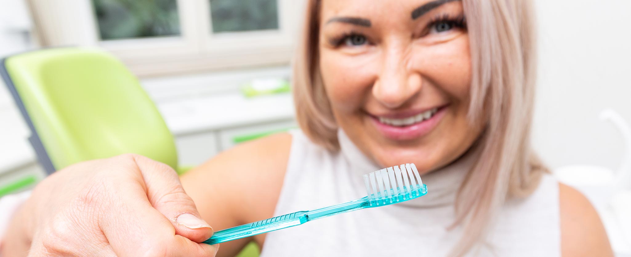 Zahnarztpraxis Totolici - lachende Patientin mit Zahnbürste